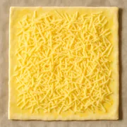 Geriebenen Käse auf den Blätterteig streuen