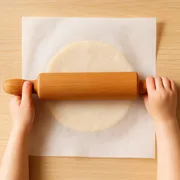 Plätzchenteig zwischen zwei Bögen Backpapier ausrollen