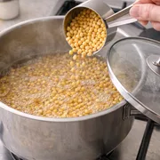 Maiskörner in den Topf geben