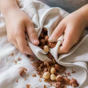 Kinderhände rubbeln geröstete Haselnüsse in einem Küchentuch