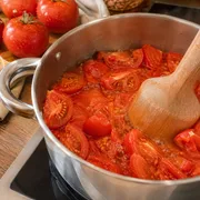 Geviertelte Tomaten im Topf erhitzen und zerdrücken