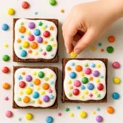 Kinderhand verziert Kuchen mit Schokolinsen